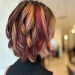 Copper magenta fashion hair color with dimensional ribbons, soft movement, and radiant shine at Box Office Hair in Winter Springs, Florida.